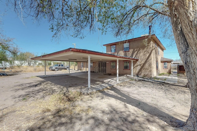 1647 Atrisco Dr SW, Albuquerque, NM 87105 - rear view of house featuring dirt driveway, an attached carport, and stucco siding
