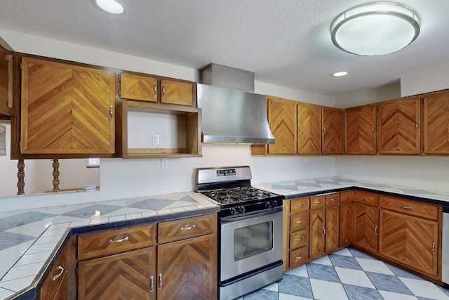 1647 Atrisco Dr SW, Albuquerque, NM 87105 - kitchen featuring stainless steel gas range oven, wall chimney range hood, brown cabinetry, tile counters, and recessed lighting