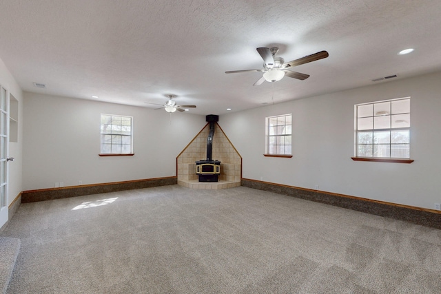 1647 Atrisco Dr SW, Albuquerque, NM 87105 - carpeted empty room featuring a wood stove, baseboards, ceiling fan, recessed lighting, and a textured ceiling