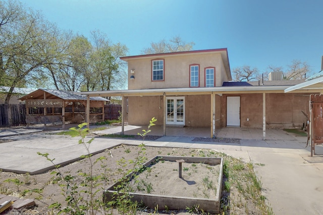 1647 Atrisco Dr SW, Albuquerque, NM 87105 - back of property featuring french doors, a vegetable garden, a patio area, a gazebo, and stucco siding