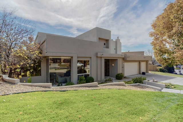 adobe home with an attached garage, driveway, stucco siding, and a front yard