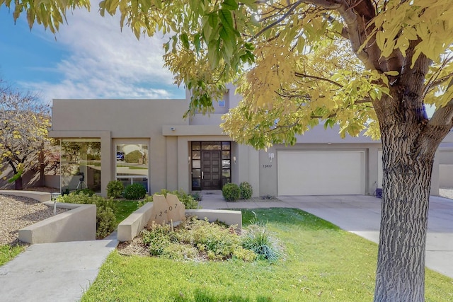 view of front of property featuring concrete driveway, a front yard, and stucco siding