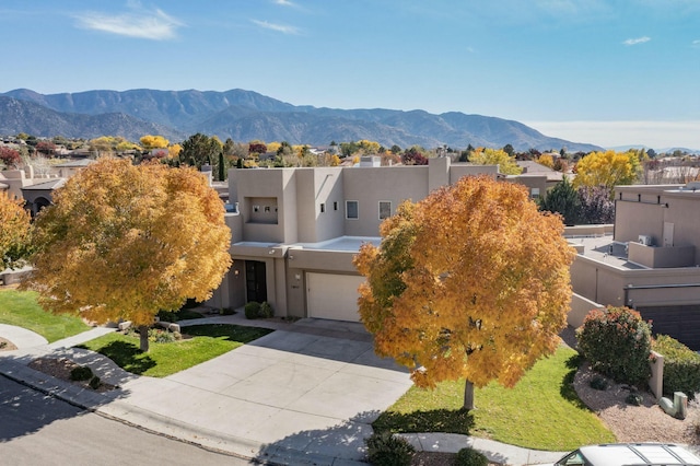 view of front of property featuring a garage, a residential view, stucco siding, a mountain view, and driveway