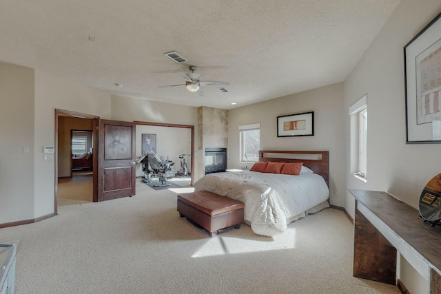 carpeted bedroom featuring visible vents, baseboards, a ceiling fan, and a textured ceiling