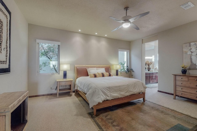 bedroom with baseboards, light carpet, ensuite bathroom, a textured ceiling, and visible vents