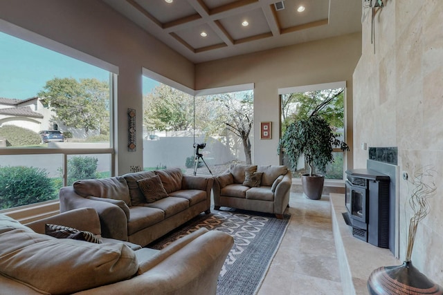 sunroom / solarium with beam ceiling, a wood stove, coffered ceiling, and a healthy amount of sunlight