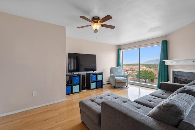 2700 Vista Grande Dr NW Unit 56, Albuquerque, NM 87120 - living room featuring baseboards, a baseboard radiator, ceiling fan, a fireplace, and wood finished floors