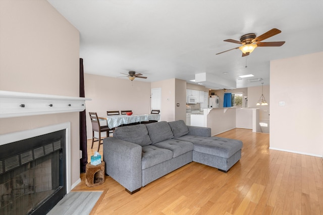 2700 Vista Grande Dr NW Unit 56, Albuquerque, NM 87120 - living area featuring a fireplace with flush hearth, baseboards, a ceiling fan, and light wood-style flooring