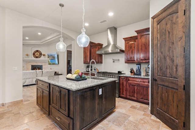 2912 William St SE, Albuquerque, NM 87102 - kitchen featuring high end stainless steel range, stone tile floors, wall chimney exhaust hood, and a sink