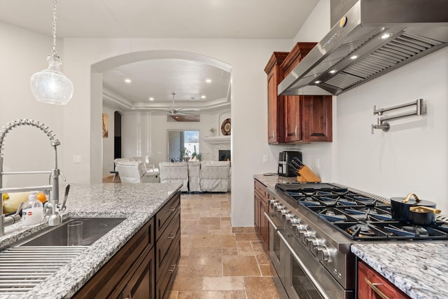 2912 William St SE, Albuquerque, NM 87102 - kitchen with stone tile floors, wall chimney range hood, a sink, arched walkways, and range with two ovens