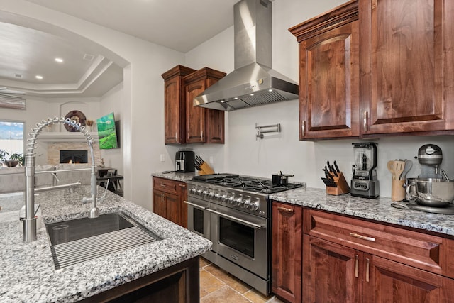 2912 William St SE, Albuquerque, NM 87102 - kitchen with arched walkways, exhaust hood, range with two ovens, light stone countertops, and a lit fireplace
