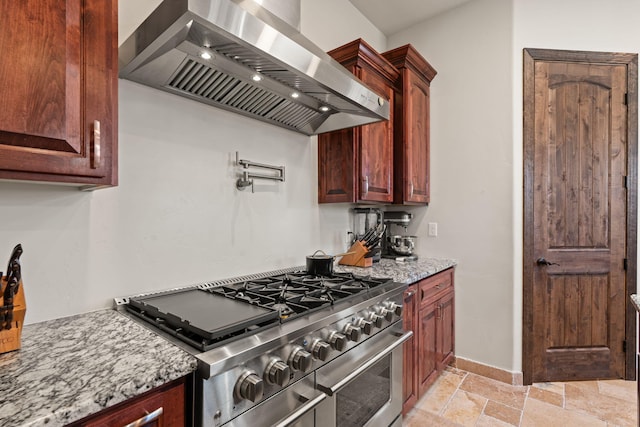 2912 William St SE, Albuquerque, NM 87102 - kitchen featuring stone tile floors, wall chimney exhaust hood, light stone countertops, baseboards, and range with two ovens