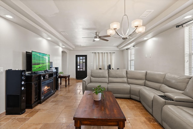 2912 William St SE, Albuquerque, NM 87102 - living area featuring a tray ceiling, a glass covered fireplace, stone tile floors, and ceiling fan with notable chandelier