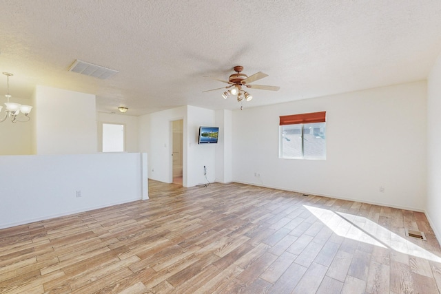 2740 Wilder Loop NE, Rio Rancho, NM 87144 - empty room with visible vents, ceiling fan with notable chandelier, light wood-type flooring, and a textured ceiling