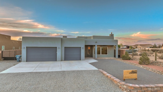 4621 27th Ave NE, Rio Rancho, NM 87144 - adobe home with gravel driveway, a garage, stucco siding, and a chimney