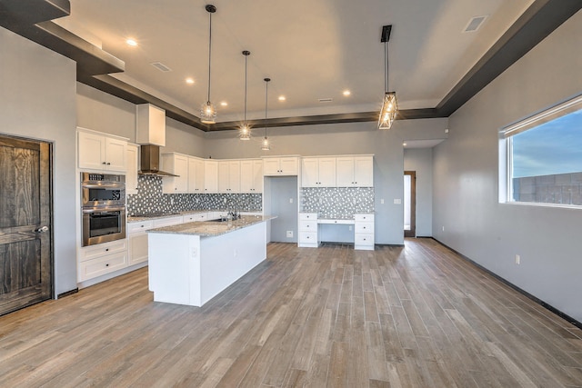 4621 27th Ave NE, Rio Rancho, NM 87144 - kitchen featuring appliances with stainless steel finishes, a sink, a tray ceiling, tasteful backsplash, and light wood-style flooring