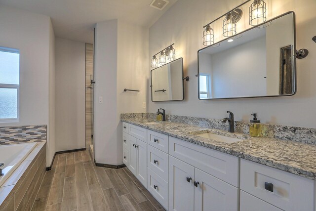 4621 27th Ave NE, Rio Rancho, NM 87144 - full bath featuring plenty of natural light, double vanity, tiled tub, and wood finished floors