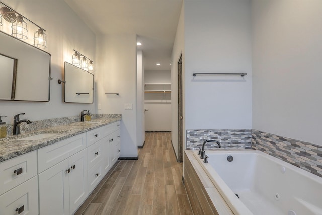 4621 27th Ave NE, Rio Rancho, NM 87144 - full bathroom featuring wood finished floors, a whirlpool tub, double vanity, a walk in closet, and recessed lighting