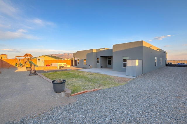 4621 27th Ave NE, Rio Rancho, NM 87144 - back of house with stucco siding, a patio area, and a playground