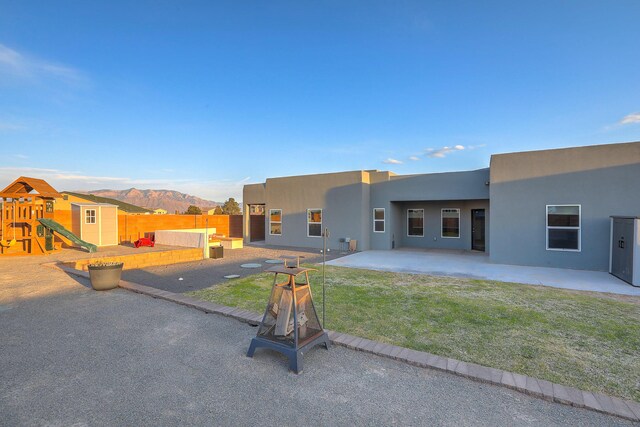 4621 27th Ave NE, Rio Rancho, NM 87144 - rear view of property with stucco siding, a patio, a playground, a mountain view, and a storage shed
