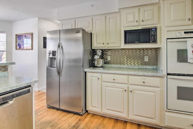 kitchen featuring backsplash, light countertops, light wood-style floors, and stainless steel appliances