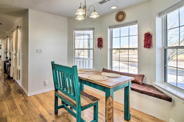 dining space with visible vents, light wood-style flooring, baseboards, and a chandelier
