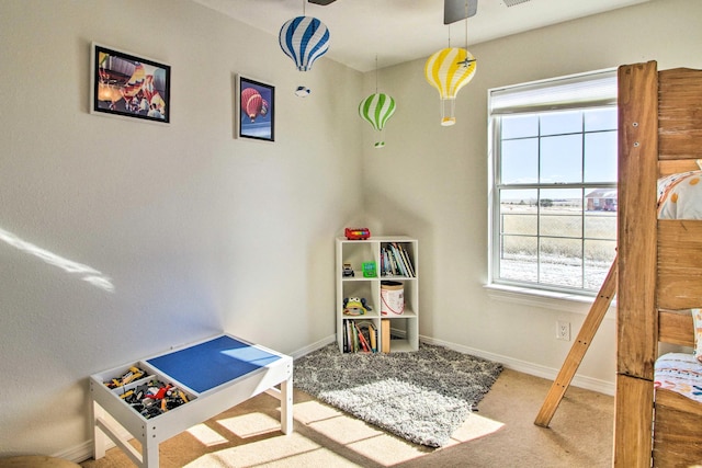 recreation room with a ceiling fan, baseboards, and carpet