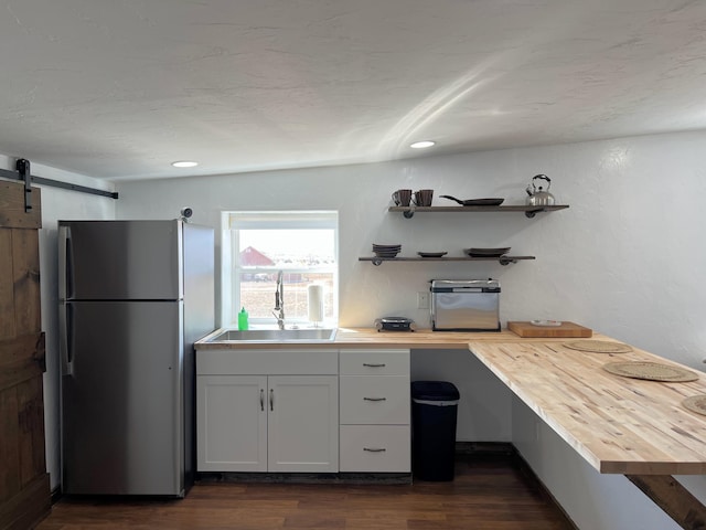 kitchen featuring a barn door, a sink, wood counters, dark wood-style floors, and freestanding refrigerator