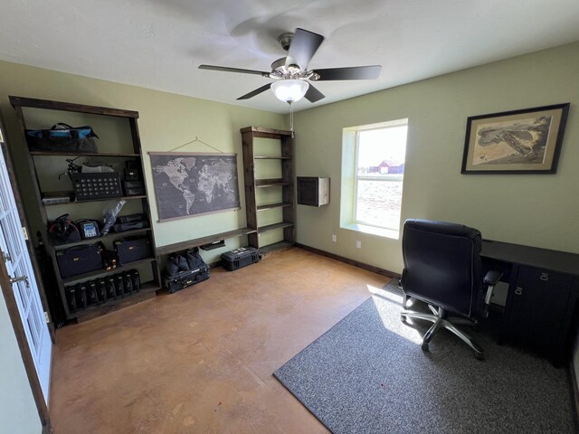 office featuring finished concrete flooring, a ceiling fan, and baseboards