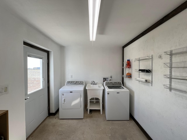 washroom featuring baseboards, a sink, independent washer and dryer, and laundry area