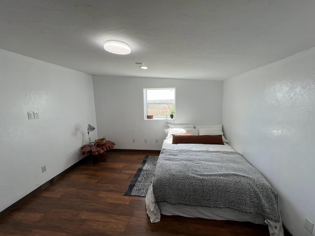bedroom featuring baseboards and dark wood-style flooring