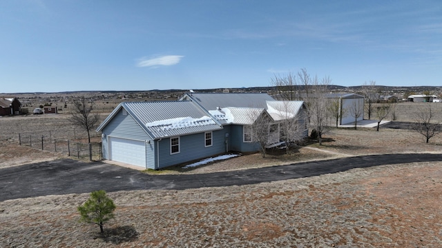 view of front facade with fence, a garage, aphalt driveway, and metal roof