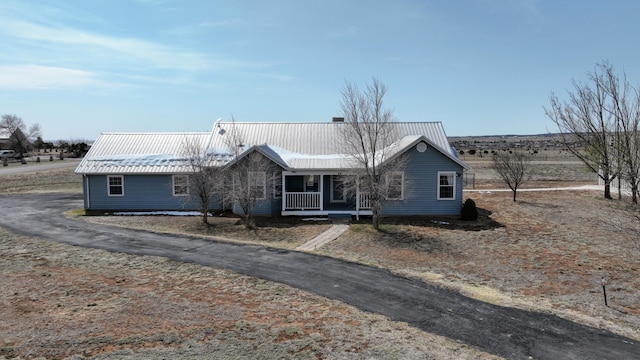 ranch-style home with a porch and metal roof