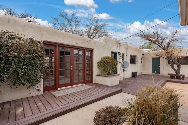 back of house with stucco siding, a deck, cooling unit, and french doors