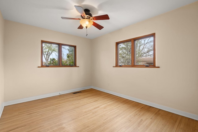 empty room with light wood-type flooring, plenty of natural light, baseboards, and visible vents