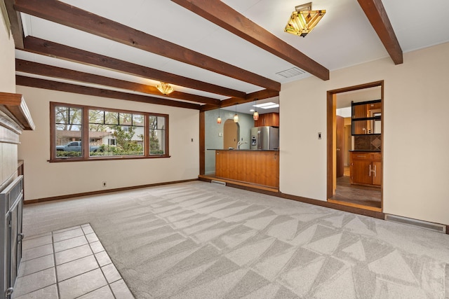 unfurnished living room with light colored carpet, beamed ceiling, visible vents, and a fireplace