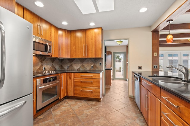 kitchen with brown cabinets, recessed lighting, stainless steel appliances, a sink, and decorative backsplash