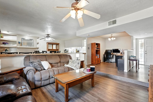living room featuring a textured ceiling, wood finished floors, ceiling fan, and visible vents