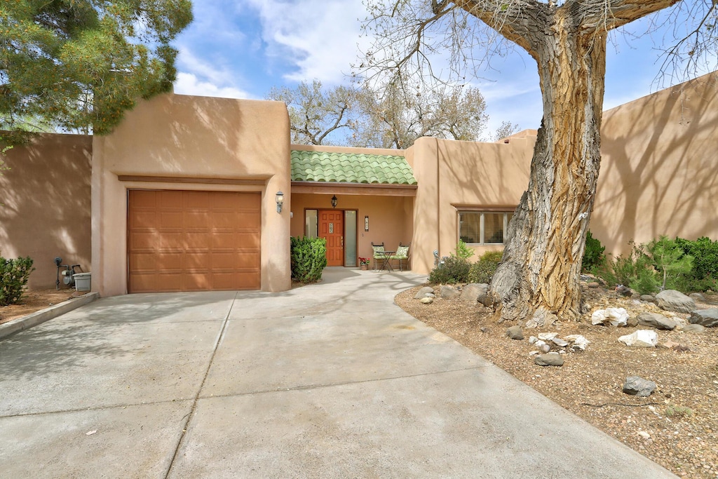 3017 Calle Del Bosque NW, Albuquerque, NM 87104 - adobe home with a garage, stucco siding, a tile roof, and concrete driveway