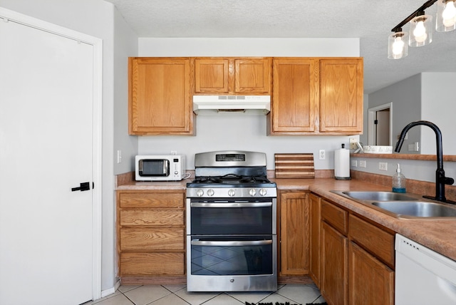 5909 Night Shadow Ave NW, Albuquerque, NM 87114 - kitchen with white appliances, under cabinet range hood, a sink, light tile patterned floors, and brown cabinetry