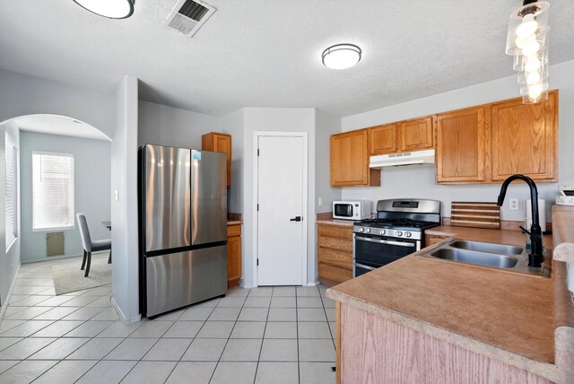 5909 Night Shadow Ave NW, Albuquerque, NM 87114 - kitchen featuring stainless steel appliances, under cabinet range hood, a sink, arched walkways, and light tile patterned floors
