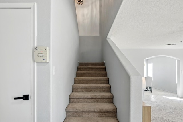 5909 Night Shadow Ave NW, Albuquerque, NM 87114 - staircase with arched walkways, a textured ceiling, and tile patterned floors