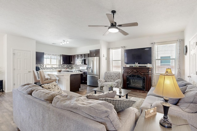 6300 Gannett Dr NE, Rio Rancho, NM 87144 - living room with a ceiling fan, dark wood-type flooring, a textured ceiling, and a glass covered fireplace