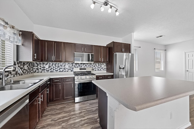 6300 Gannett Dr NE, Rio Rancho, NM 87144 - kitchen with stainless steel appliances, dark wood-style floors, dark brown cabinets, a textured ceiling, and tasteful backsplash