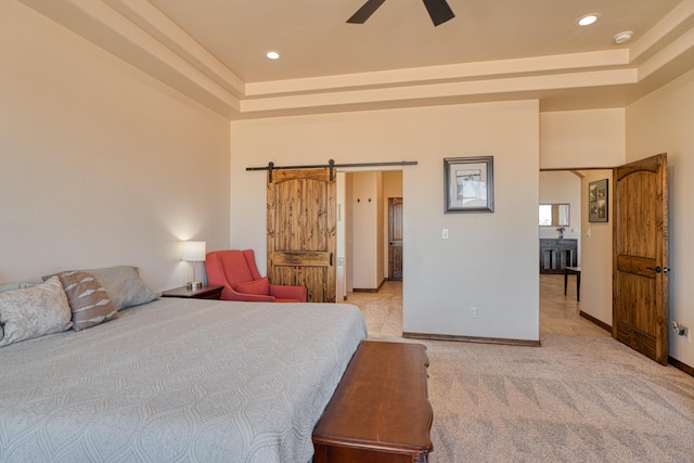 bedroom with recessed lighting, baseboards, a barn door, and a raised ceiling