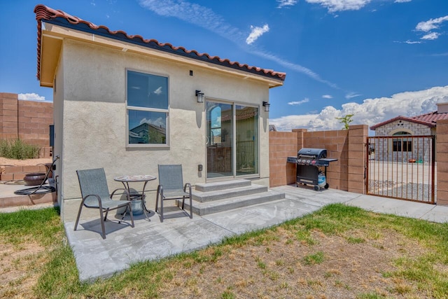 rear view of property with a patio, a gate, stucco siding, and fence