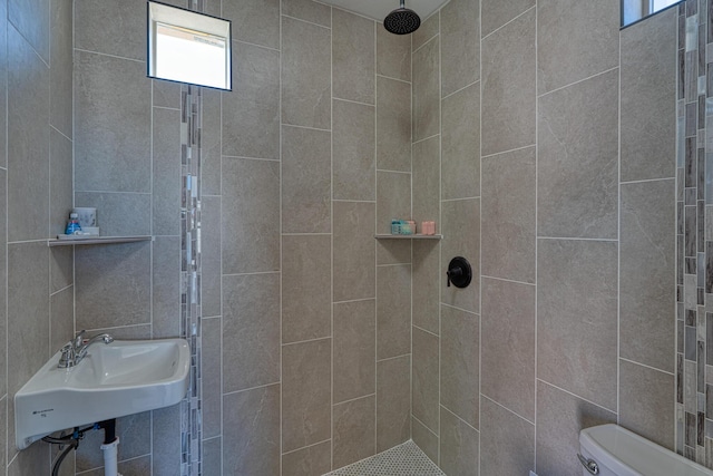 full bathroom featuring toilet, a sink, plenty of natural light, and tiled shower