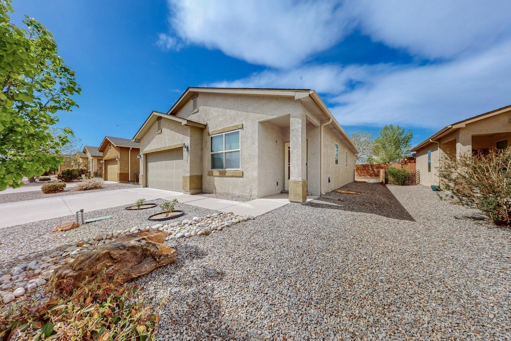 view of front of property with concrete driveway, fence, stucco siding, and a garage