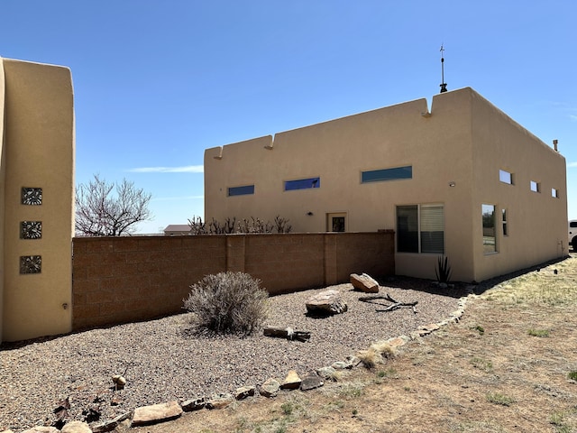 view of side of home featuring stucco siding and fence