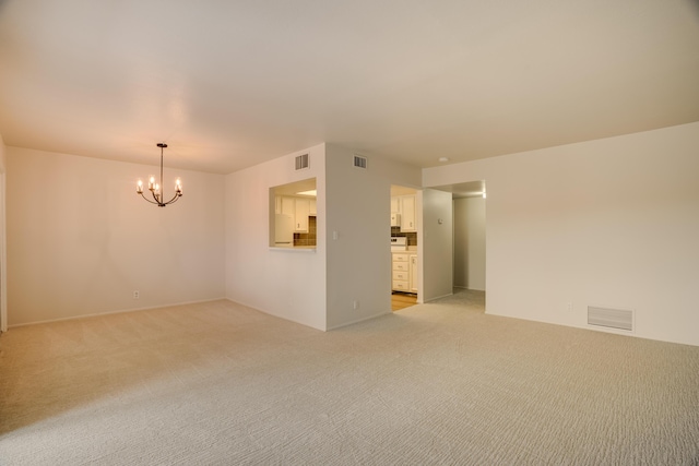 spare room with light colored carpet, a chandelier, and visible vents